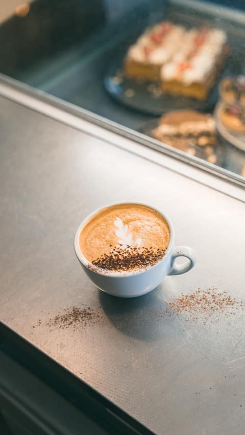 A cappuccino served beside the cake counter